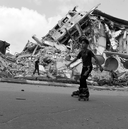 Palestinian boy rollerblades past a bombed out building in Gaza.